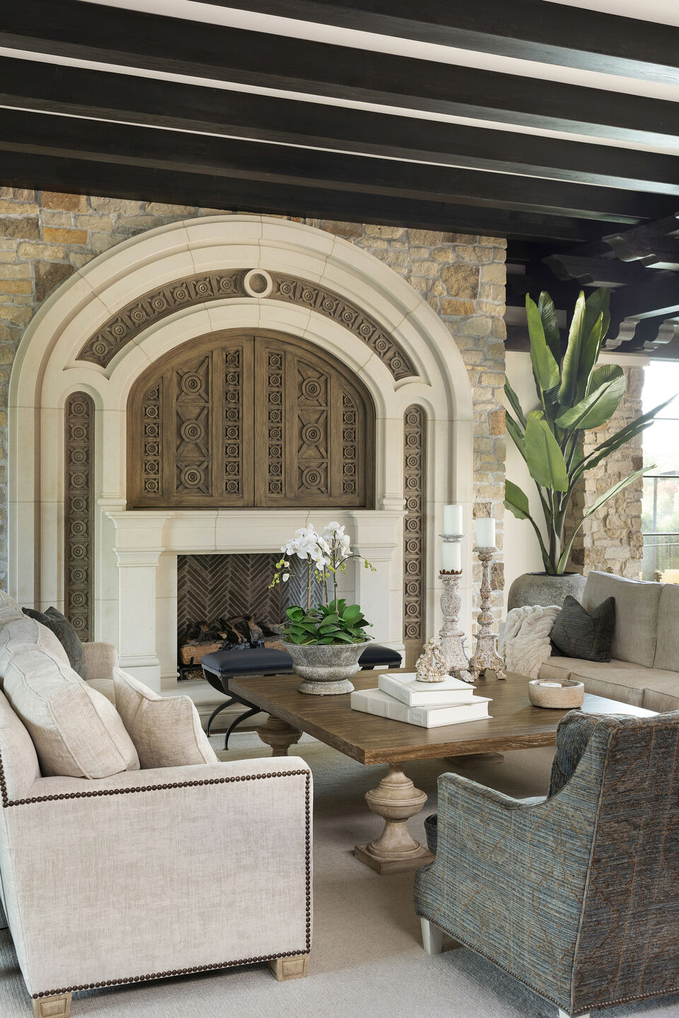 Living room with stunning fireplace design, and media center with custom hand-carved doors.