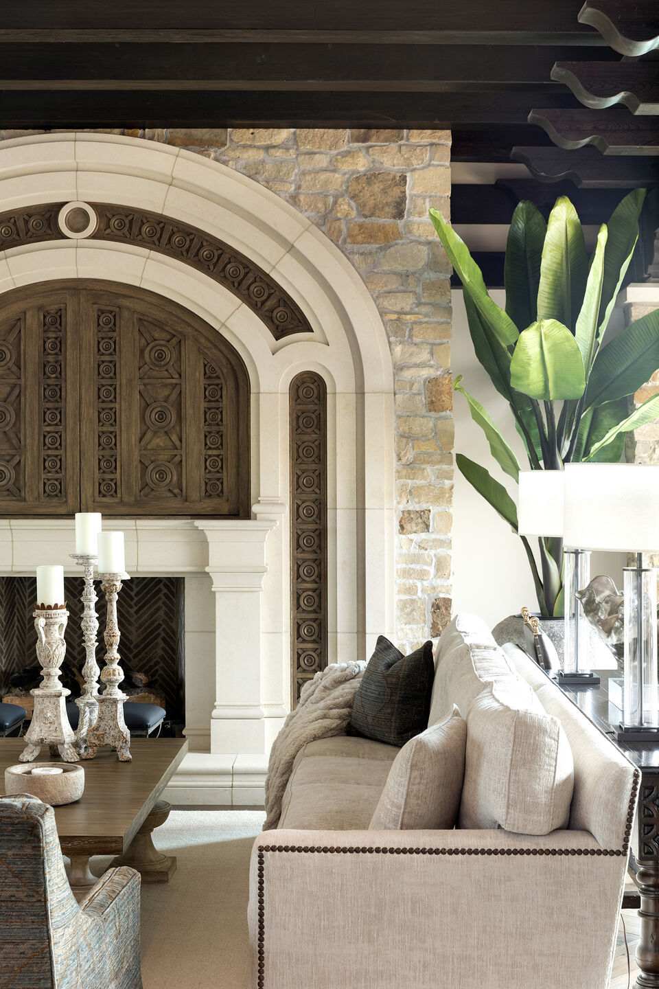 Living room with stunning fireplace design, and media center with custom hand-carved doors.
