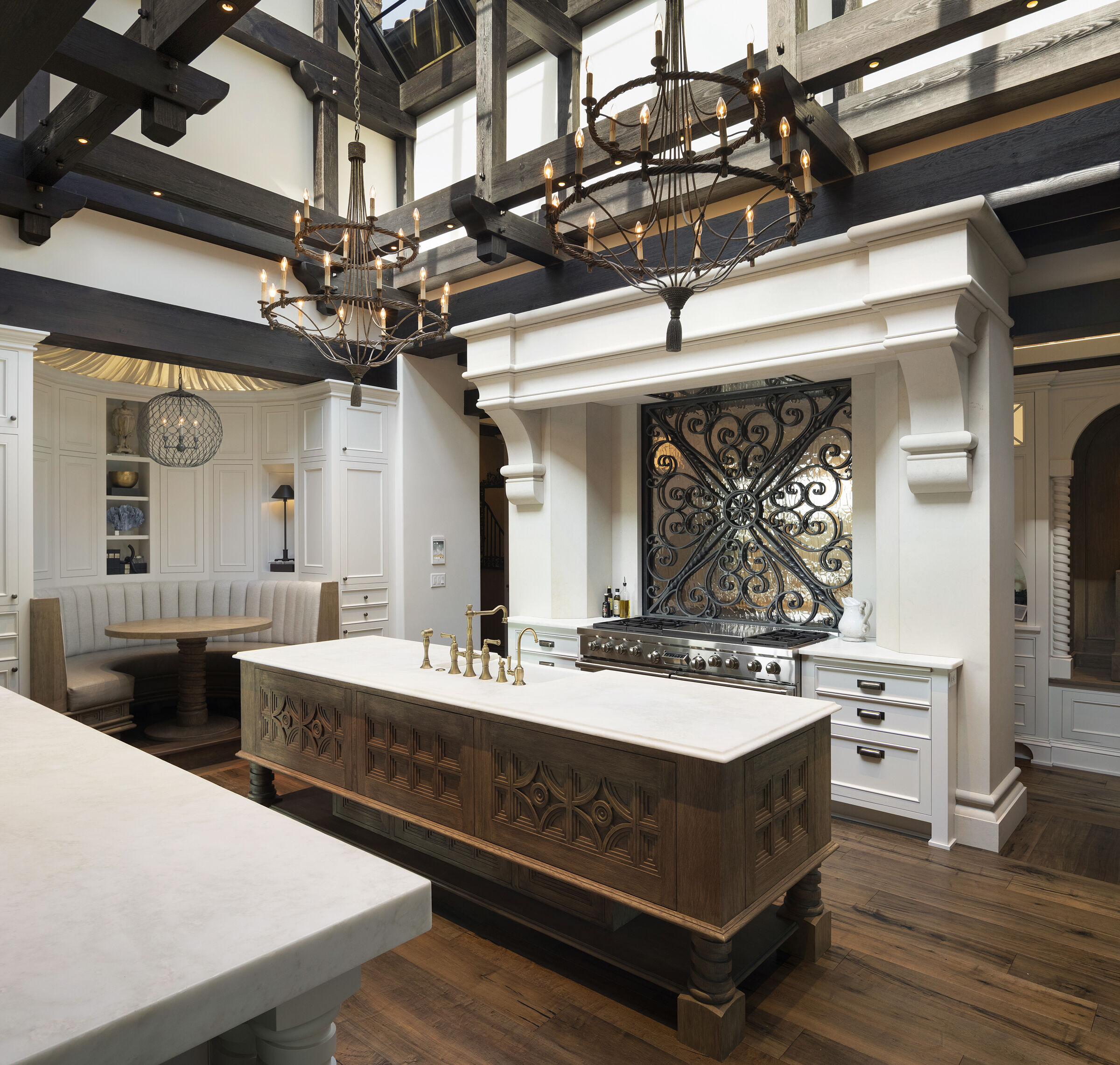 Stunning kitchen design. Skylight ceiling for natural light, beautiful wood beam details. Custom cabinetry with hand-carved wood door details. Kitchen island, breakfast nook, custom metal and glass backsplash. Gorgeous interior architecture details.