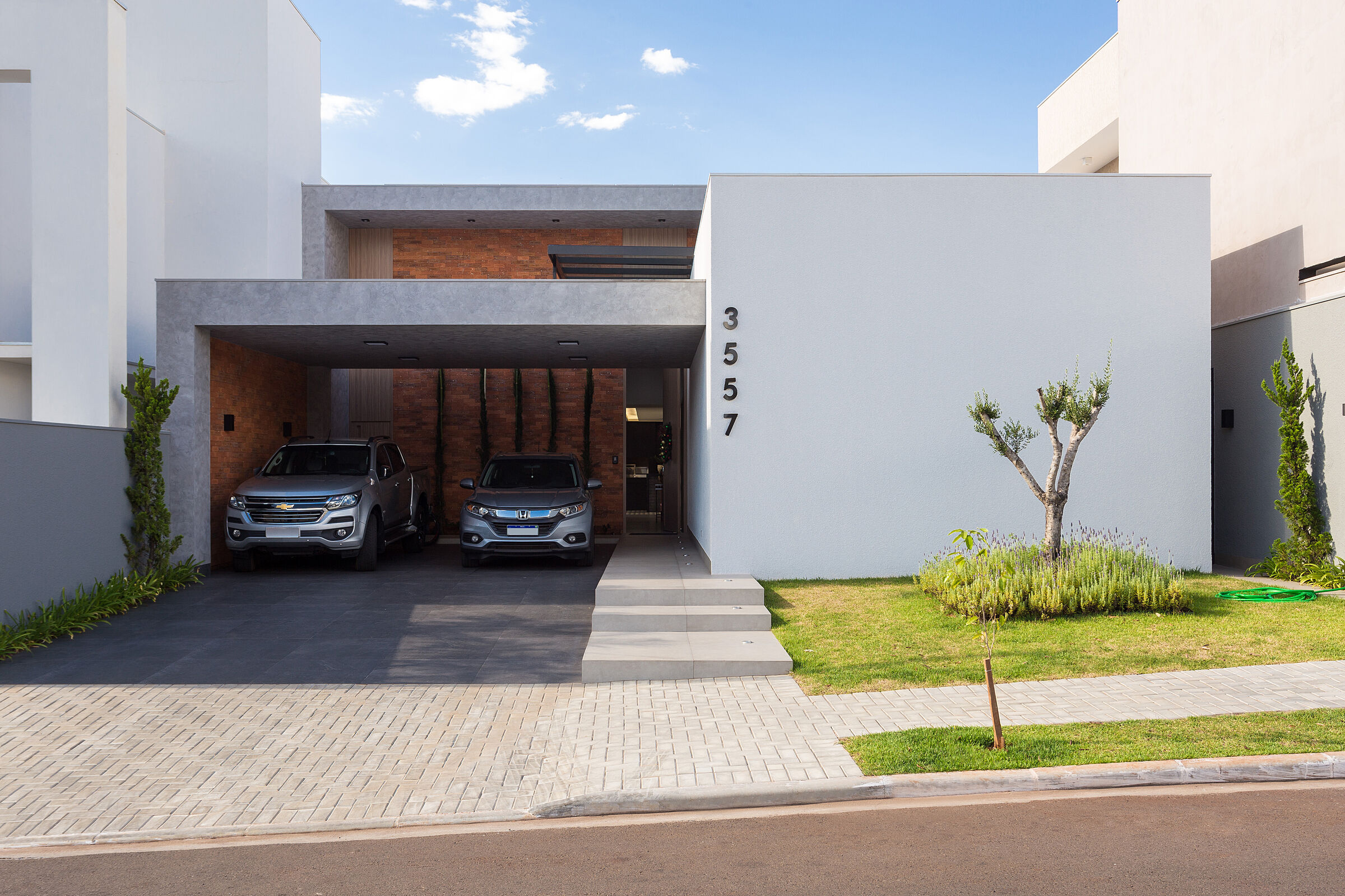 Main façade with clean geometry and natural materials, featuring exposed brick and a floating concrete volume.