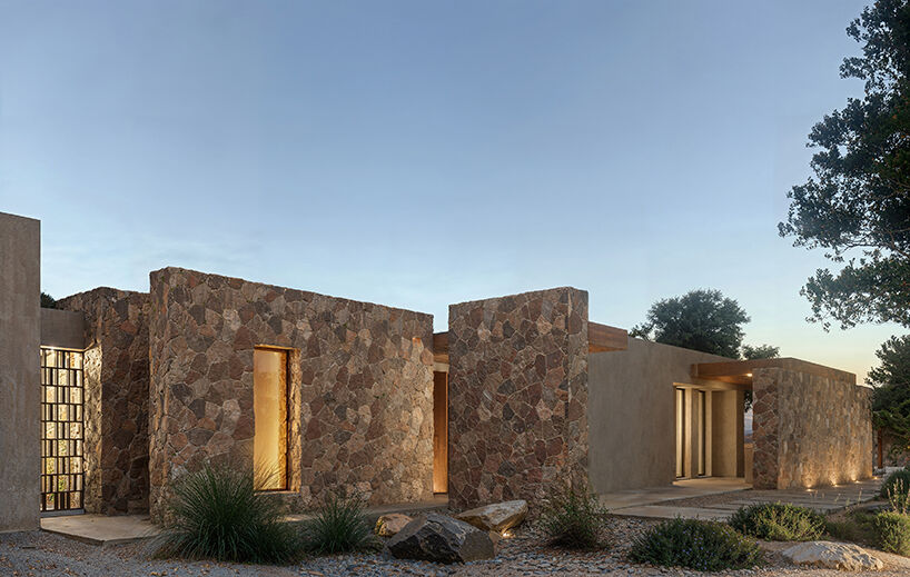 Evening view of the bedroom wing, where stone volumes and soft lighting emphasize the linear rhythm of the architecture.