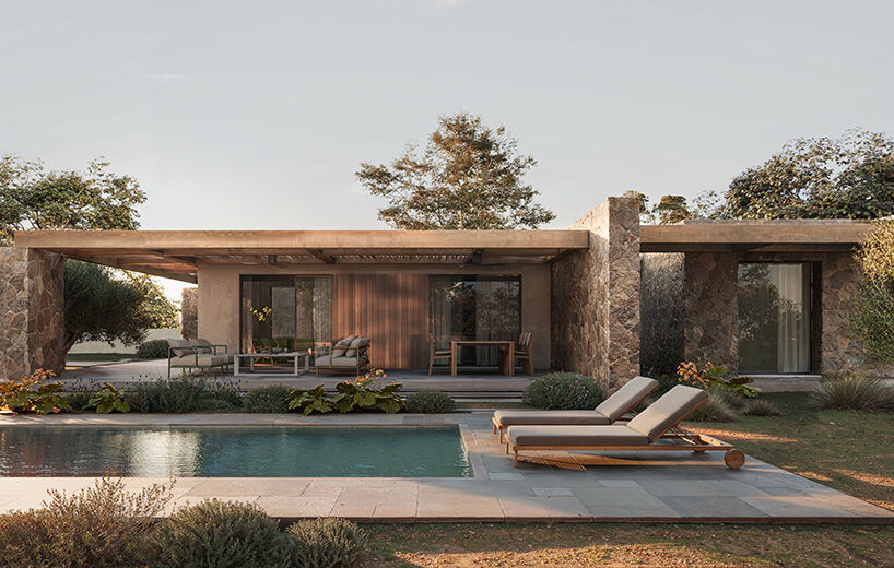 The central volume, defined by stone masses and recessed openings, anchors the architectural sequence facing the pool.