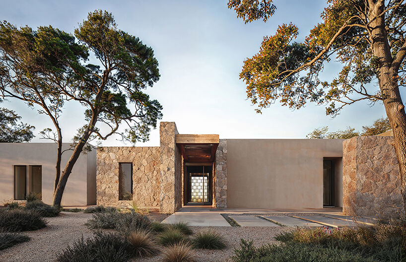 The entrance façade, where the interplay of monolithic stone and rendered surfaces establishes the project’s quiet material palette.