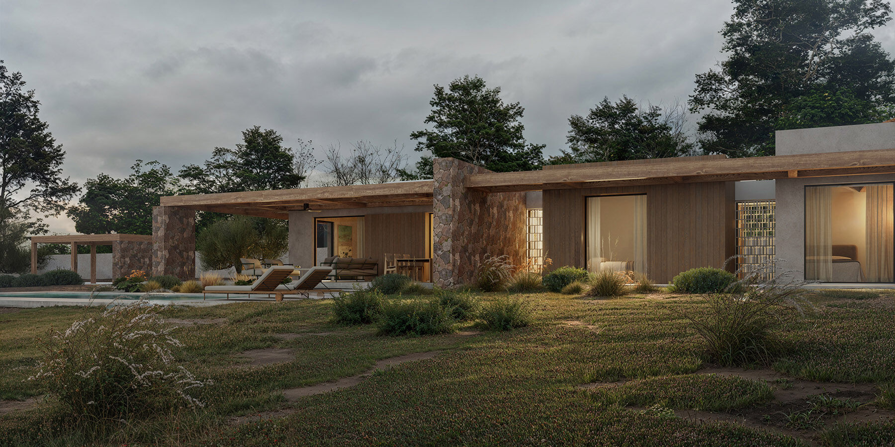 The main façade at dusk, where stone walls, timber pergolas and soft landscape planting frame the linear composition of the residence.