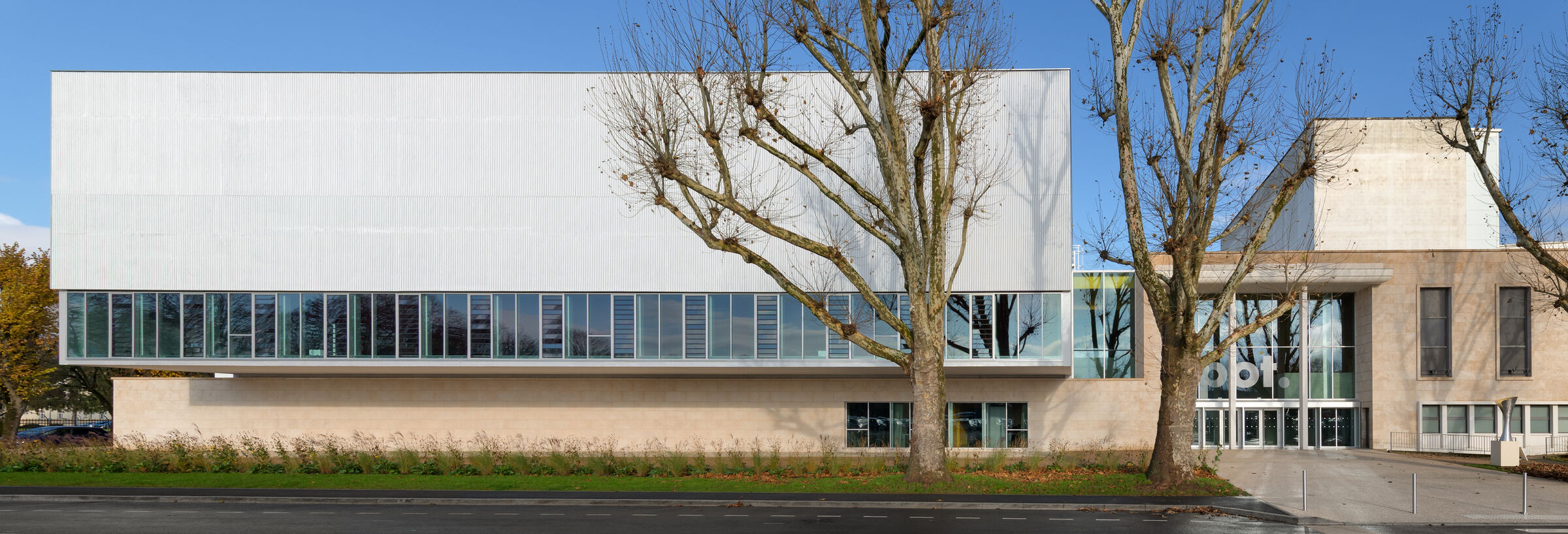 View of the glass facade of the Multipurpose Sports Centre and the historic entrance of the building.