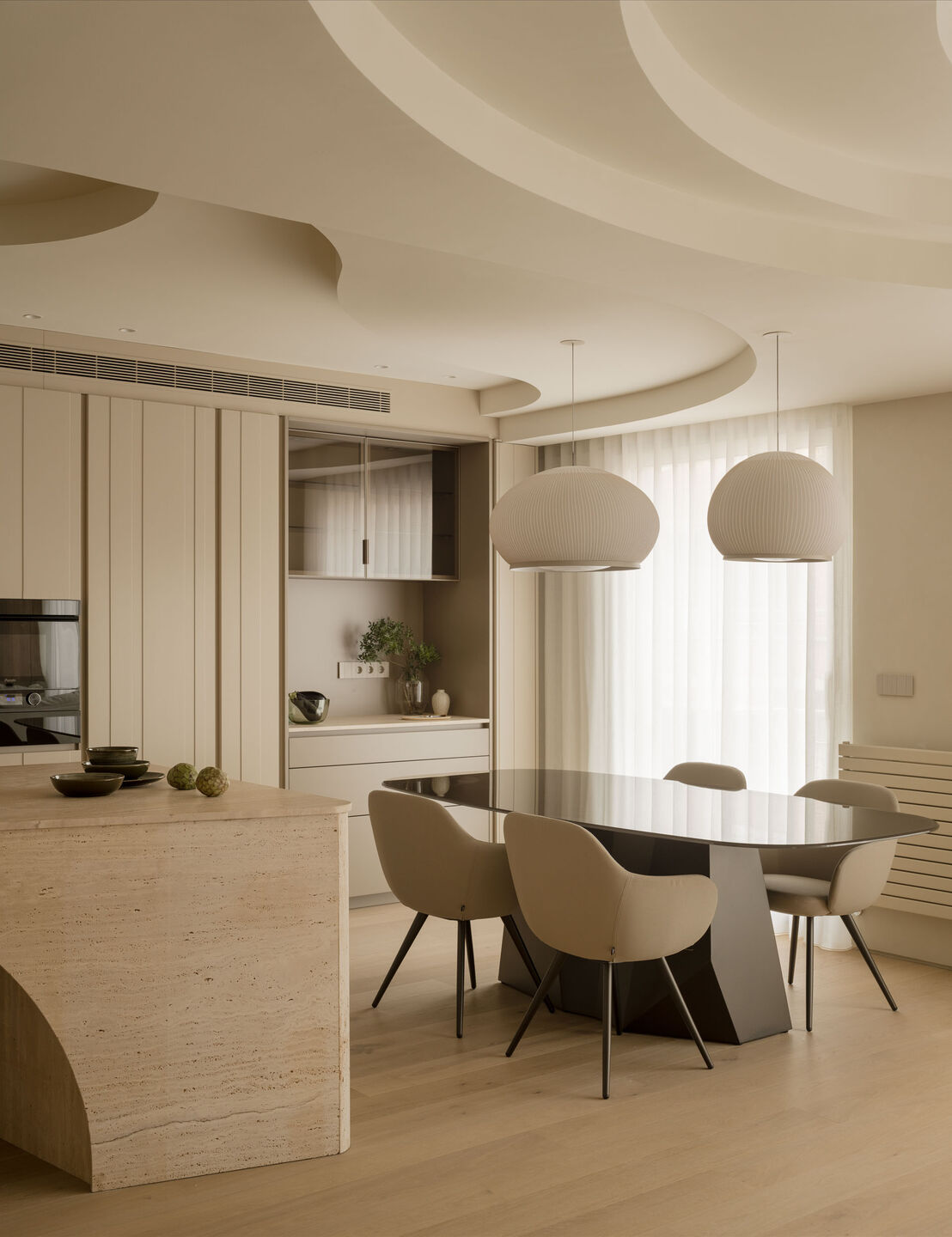 The dining room features a black glass table by Sovet, illuminated by two Knit pendant lamps by VIBIA.