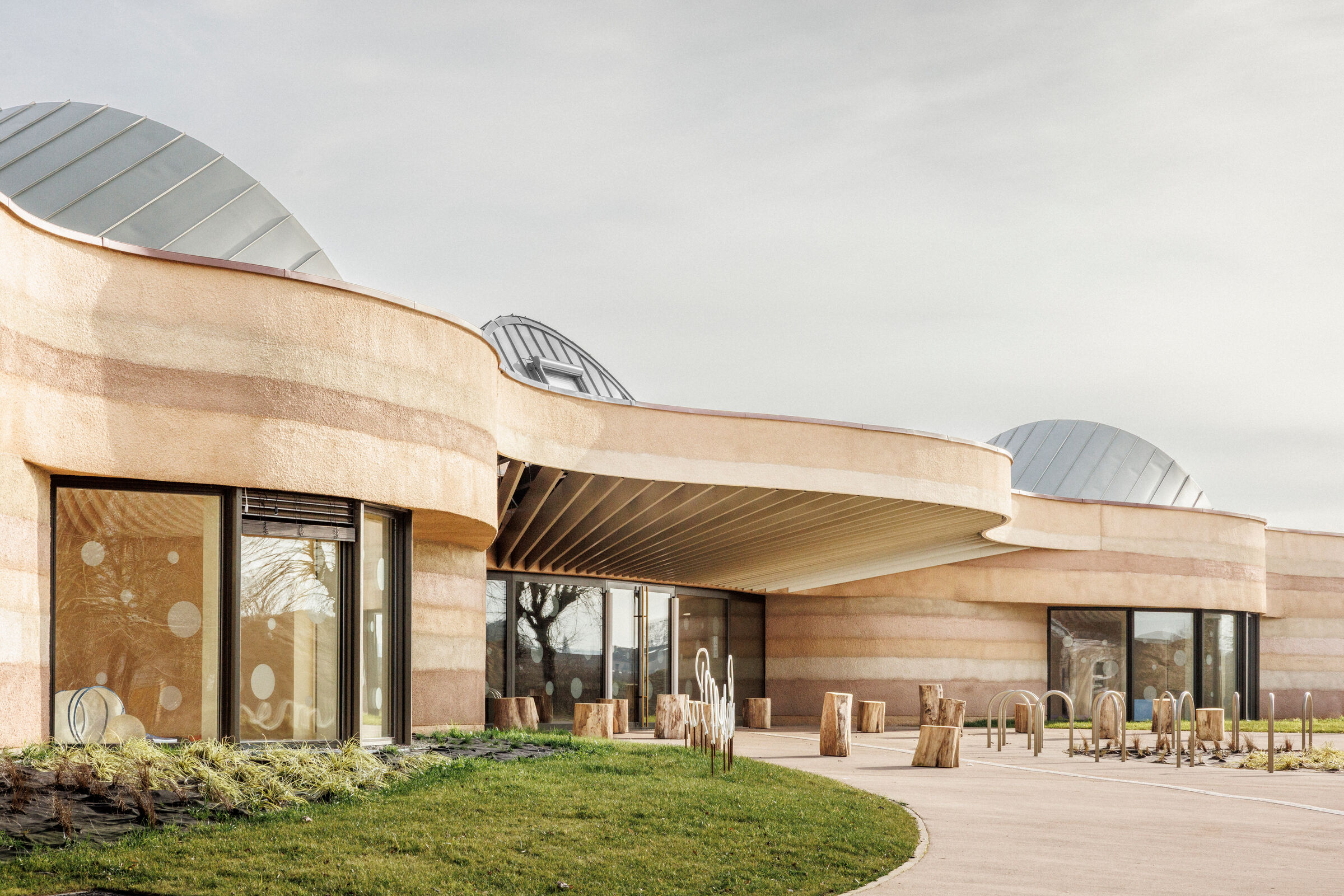 The façade's geological strata express the protection and solidity of a stone "carapace".