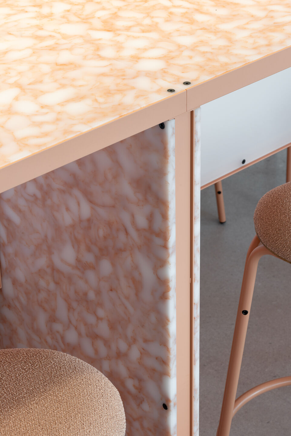Close-up of the bar counter's recycled plastic surface and visible bolt connections — a deliberate design choice that makes the demountable construction legible. The material is made from post-consumer plastic waste and designed for a second life.