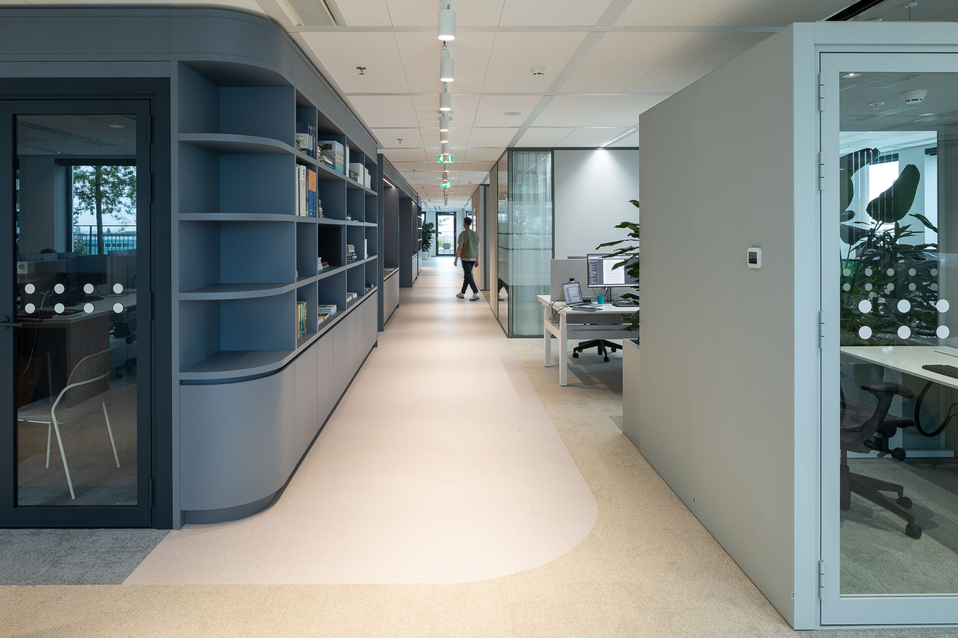 The social heart of the Sweco Utrecht office: a high bar counter clad in recycled plastic panels with a terrazzo-like appearance, surrounded by round tables on ribbed cylindrical bases. Large windows frame views across the Utrecht skyline.