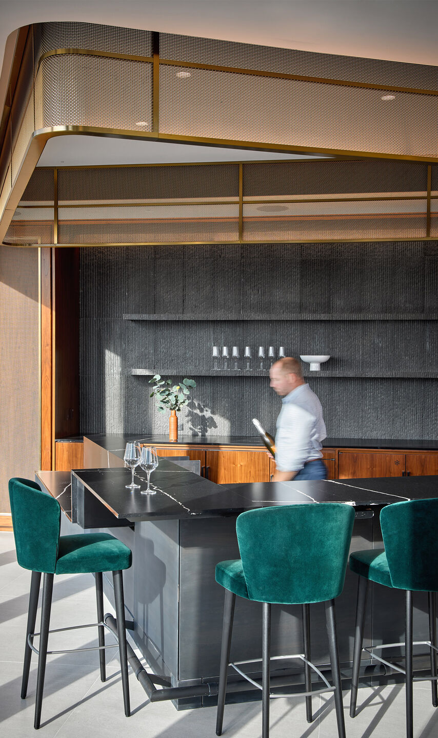 Decorative woven wire mesh installed in corporate interior design as a gantry over a bar