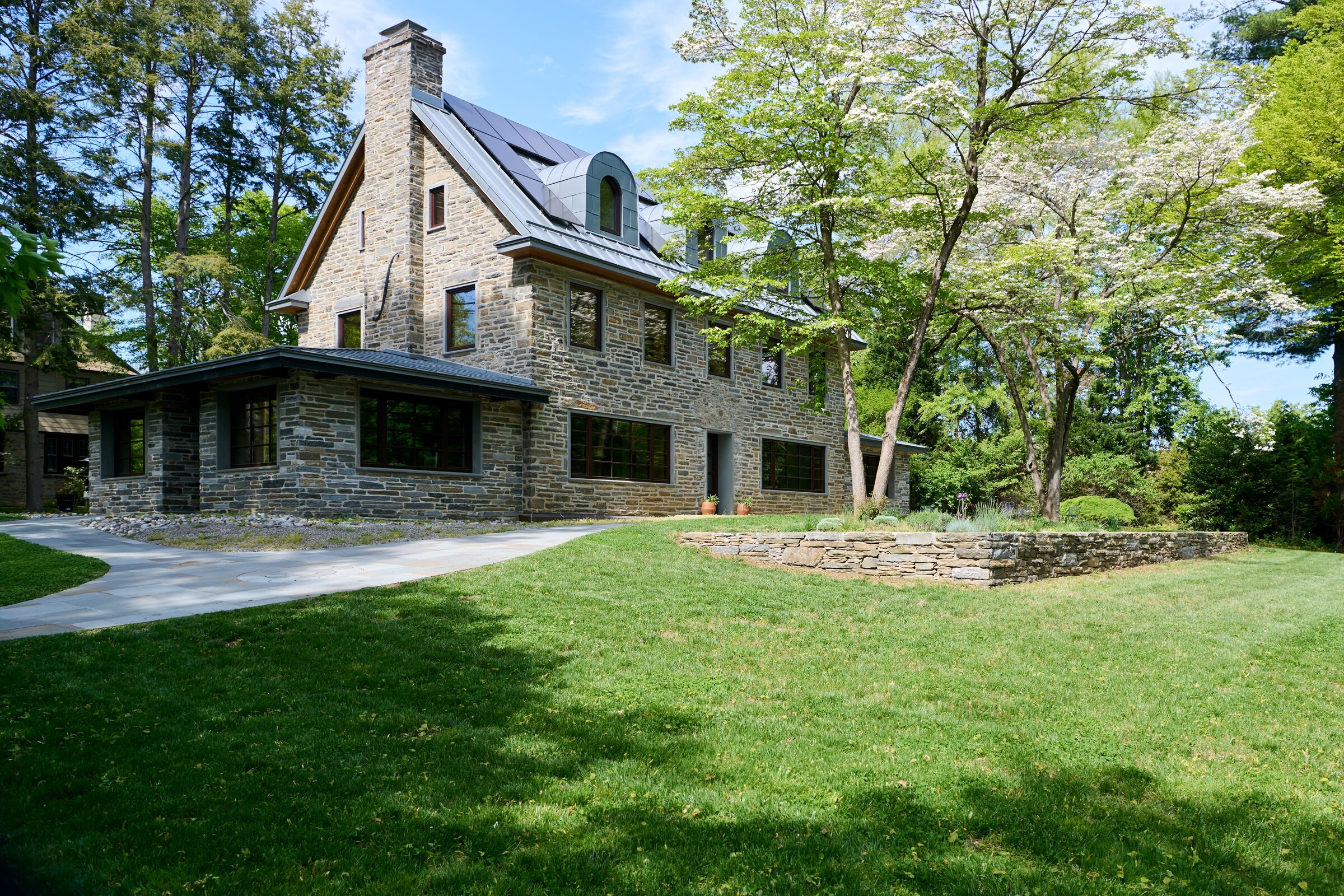 Accessible Masonry Gut Renovation - Exterior. Original Home - Horace Trumbauer, 1922.  Center high gabled area from original house. New stone additions.