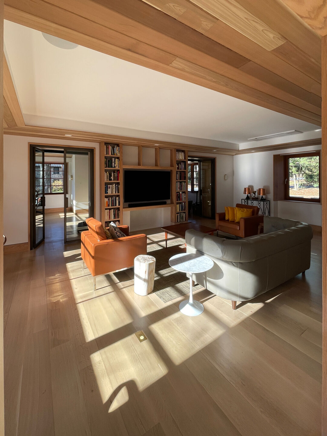 Accessible Masonry Gut Renovation - Living Room. Tray ceiling with cedar finish. Steel glass doors, custom built in cabinetry.
