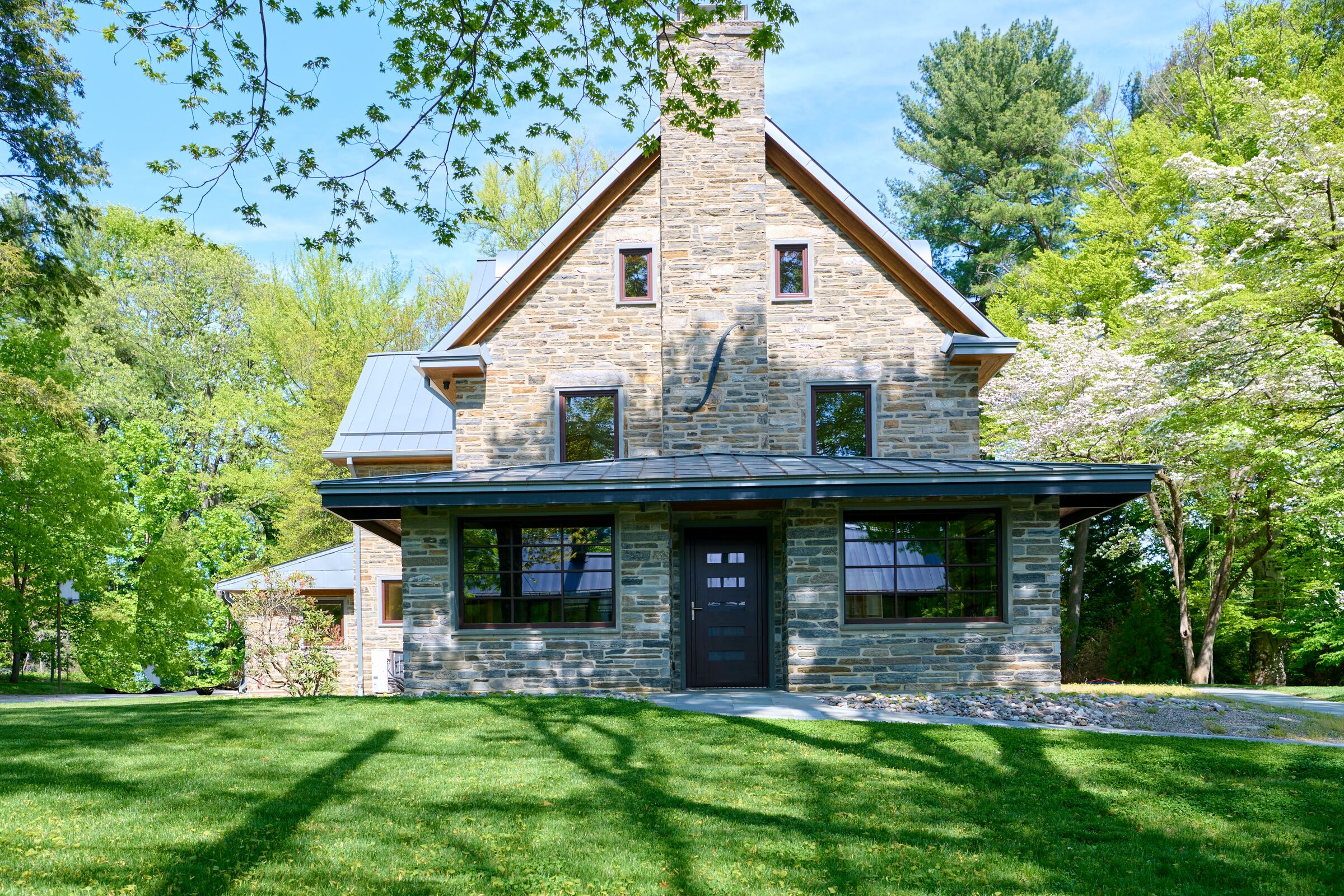 Accessible Masonry Gut Renovation - Exterior. Original Home - Horace Trumbauer, 1922.  Center high gabled area from original house. New stone additions. New street-facing elevation.
