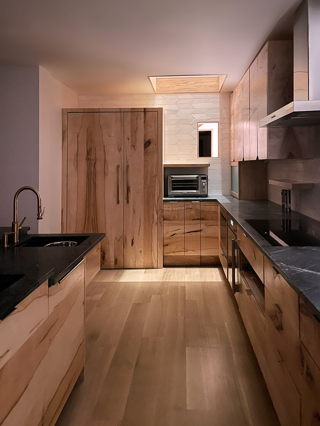 Accessible Masonry Gut Renovation - Interior. Solid maple cabinetry kitchen, made from tree on property. Illuminated at night with glass floor and staircase linear lighting.