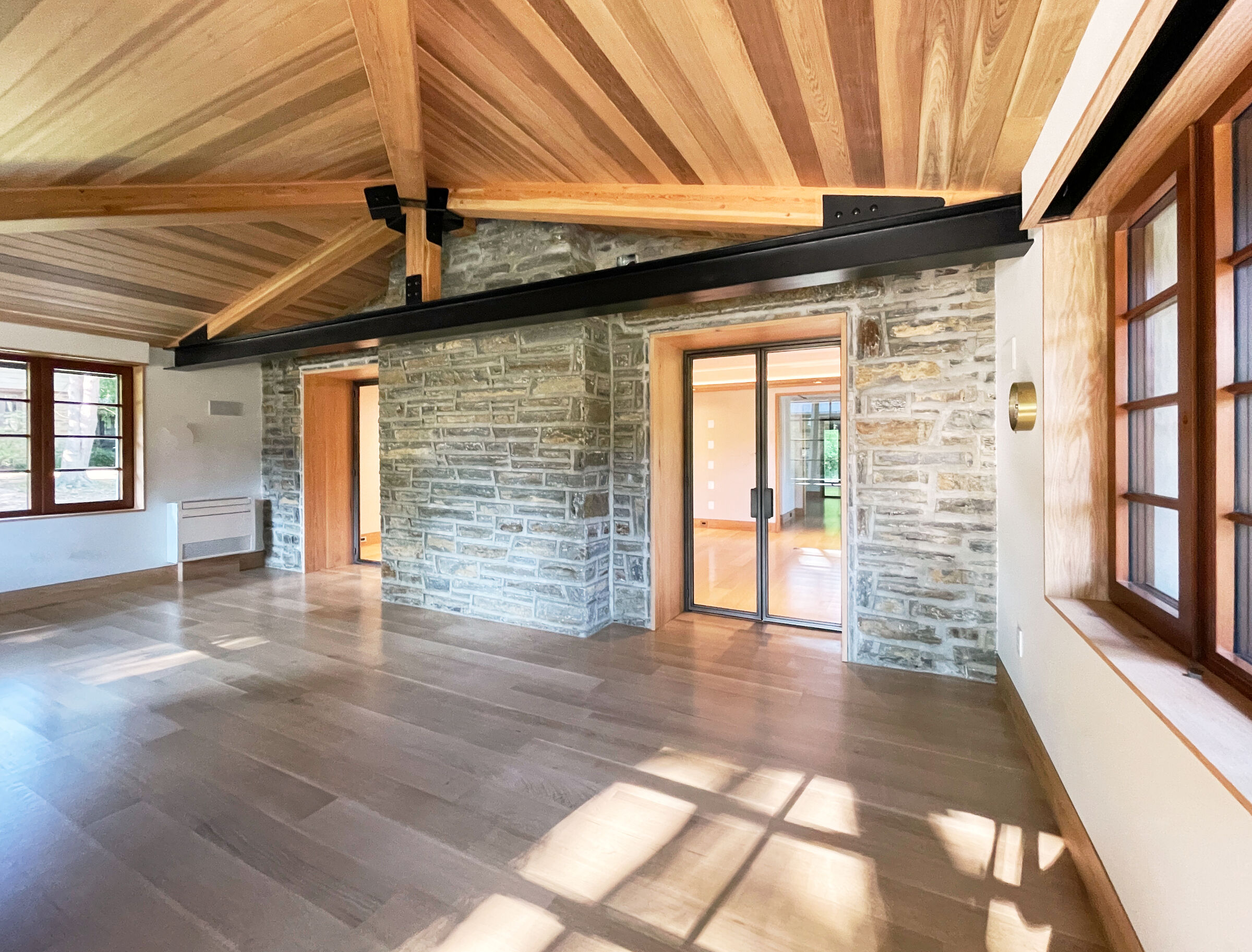 Accessible Masonry Gut Renovation - Interior. Steel hip roof tie-beam with doug-fir glulam hip beams and cedar ceiling.