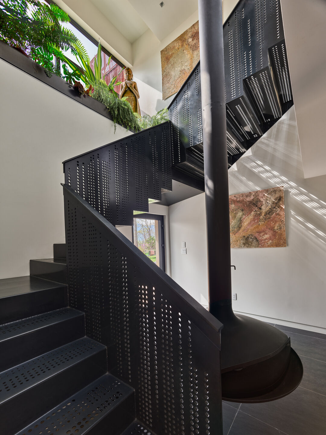 The interior stair echoes the pattern of the custom perforated Corten panels on the exterior, extending a visual language derived from mapping the songs of hoot owls recorded on site.