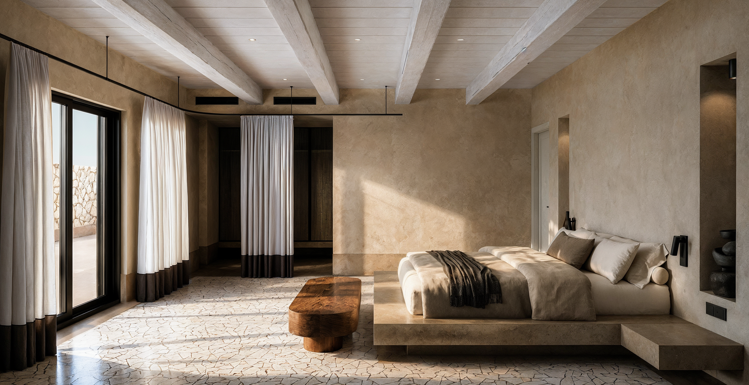 Natural stone textures, timber ceiling beams, and minimal furnishings establish a contemporary living environment inspired by the architectural heritage of Karpathos.