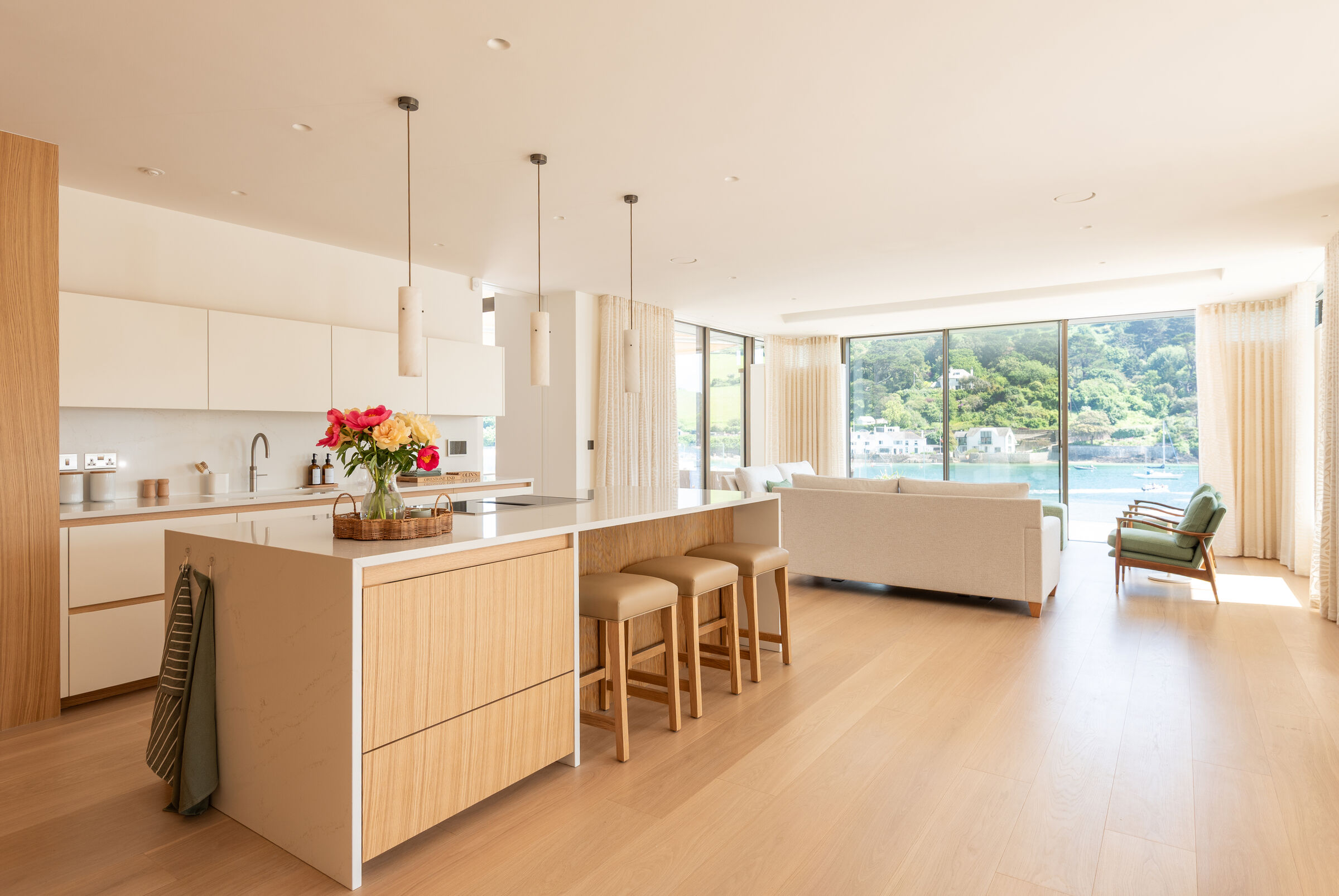 Open-plan kitchen and dining area at Orestone End with large glazed openings overlooking the sea