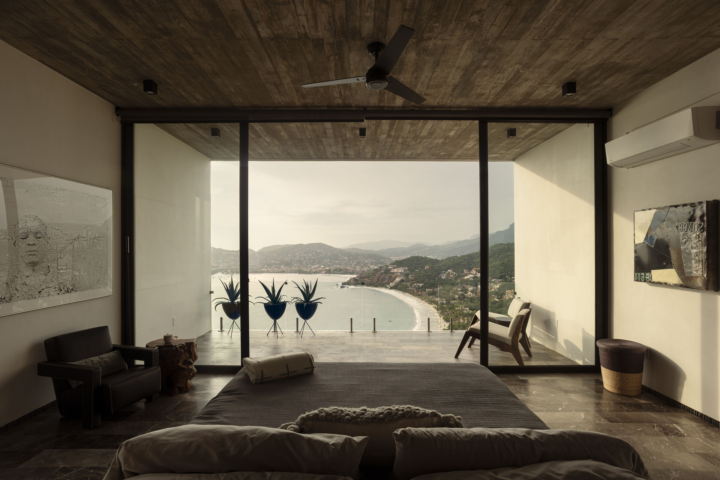 The primary bedroom opens toward the bay, turning the Pacific landscape into part of the interior.