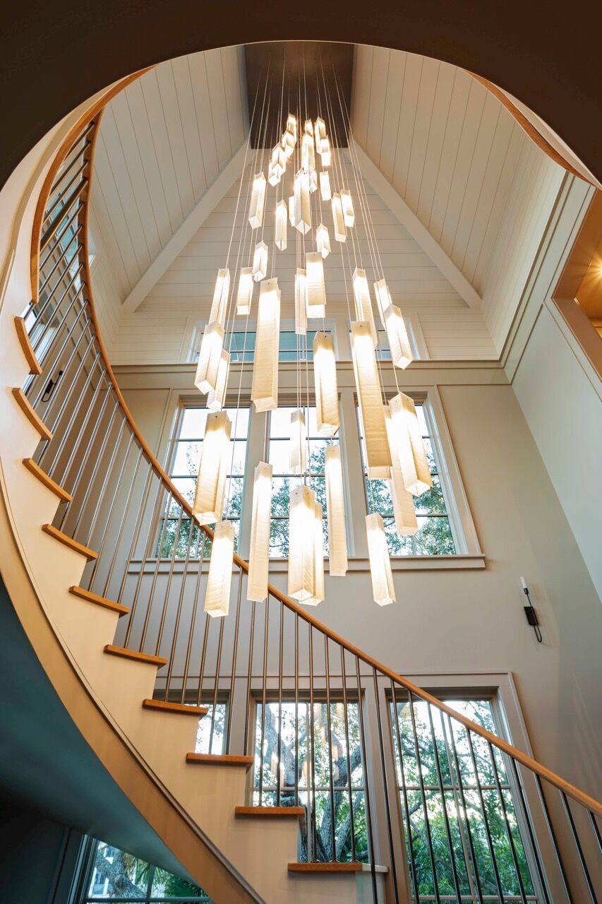 Handcrafted white glass pendants cascade through the double-height space at varying heights.