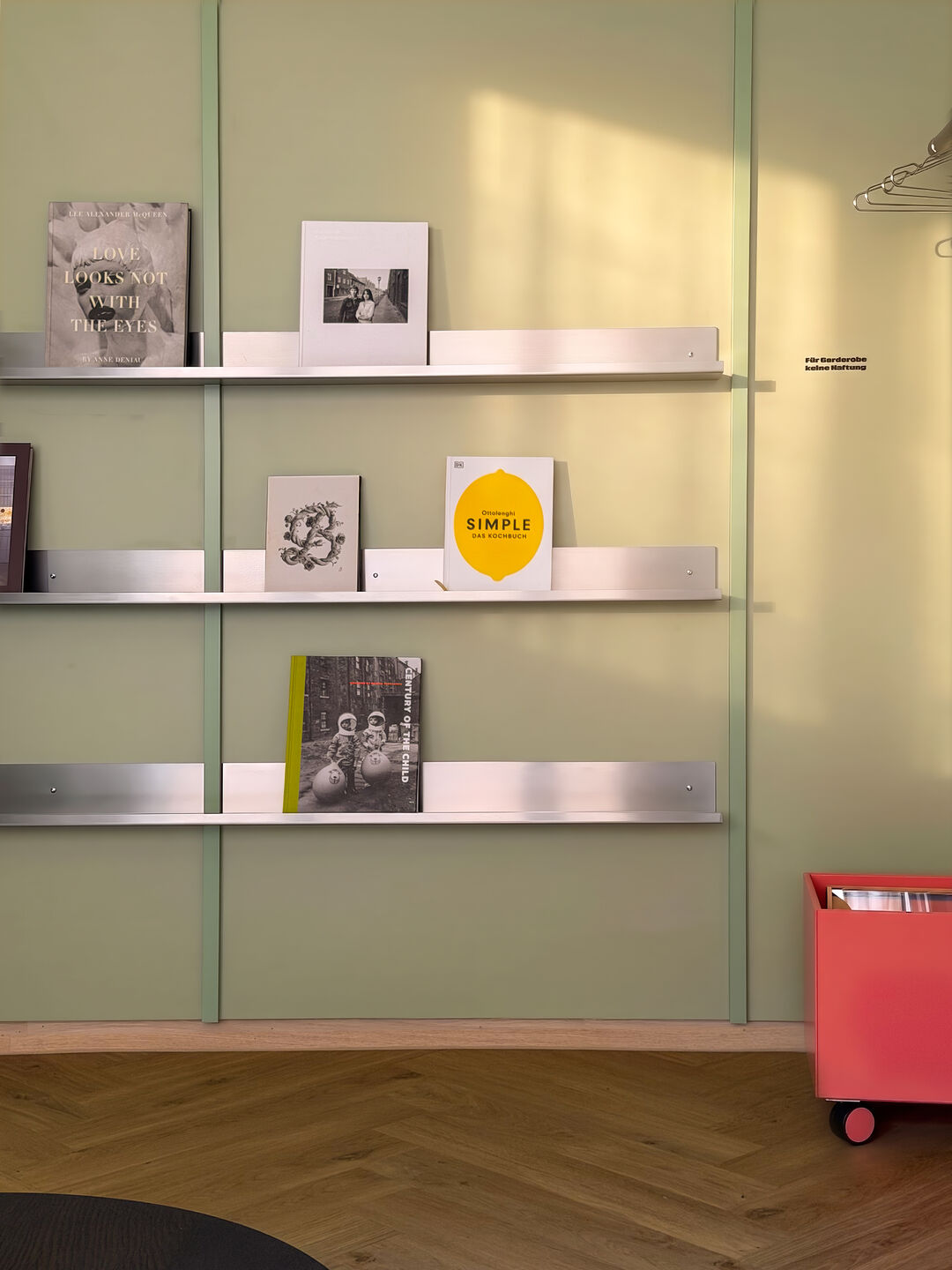 Open stainless-steel shelving displaying books, objects and selected graphic elements.
