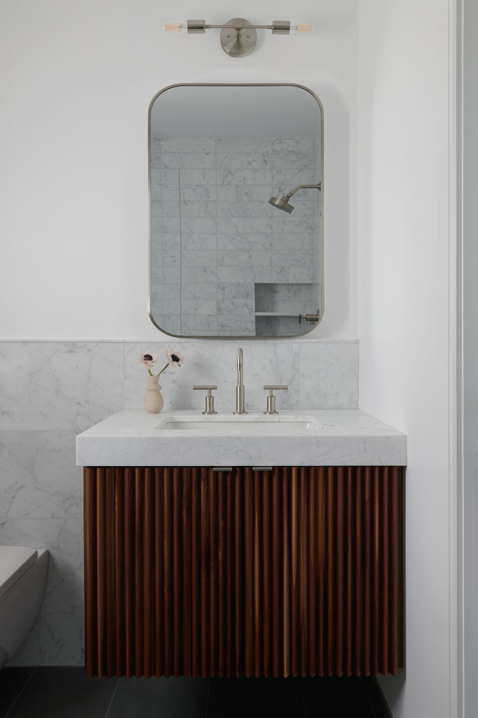 Walnut tambor panel floating vanity cabinet at guest bathroom