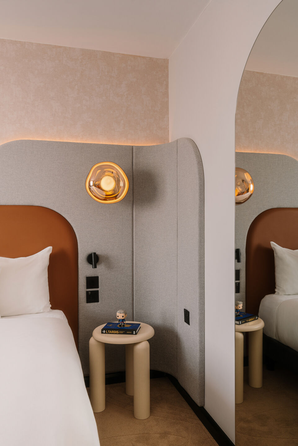 Bed with an upholstered headboard and a Tom Dixon wall lamp