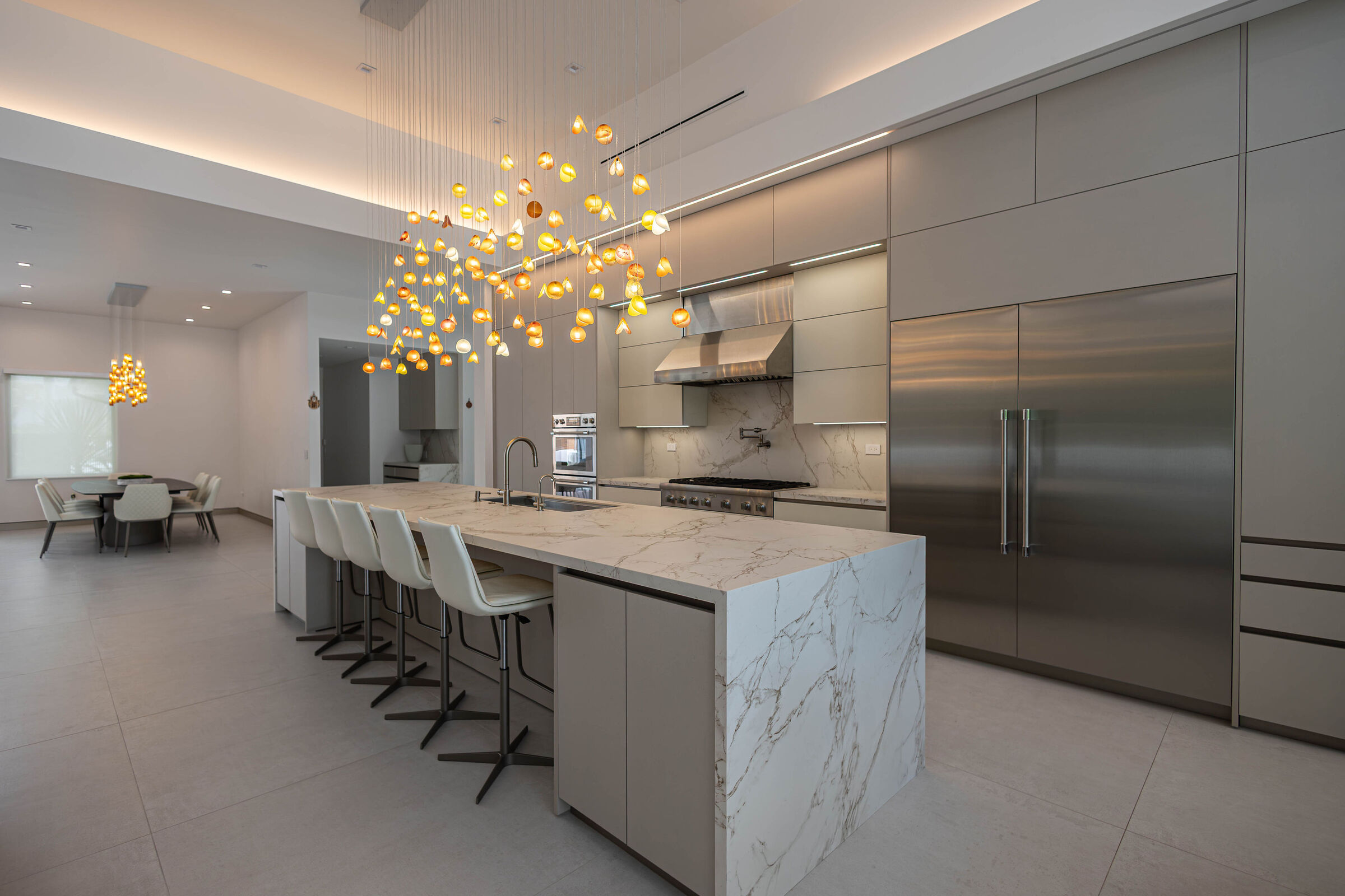 Custom glass lighting creates a warm sculptural focal point above the kitchen island
