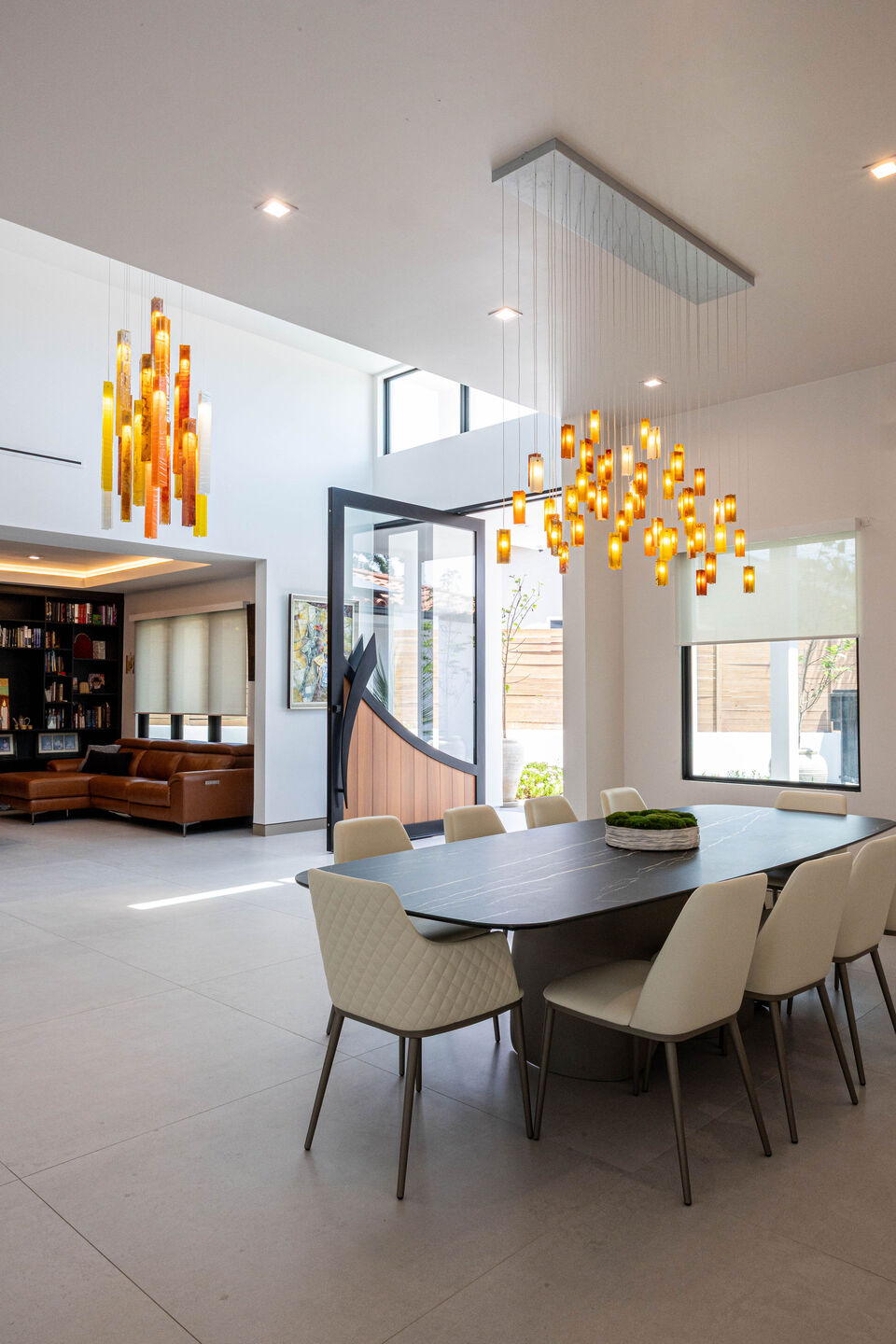 Warm handcrafted glass lighting connects the dining area and entrance through a coordinated palette.