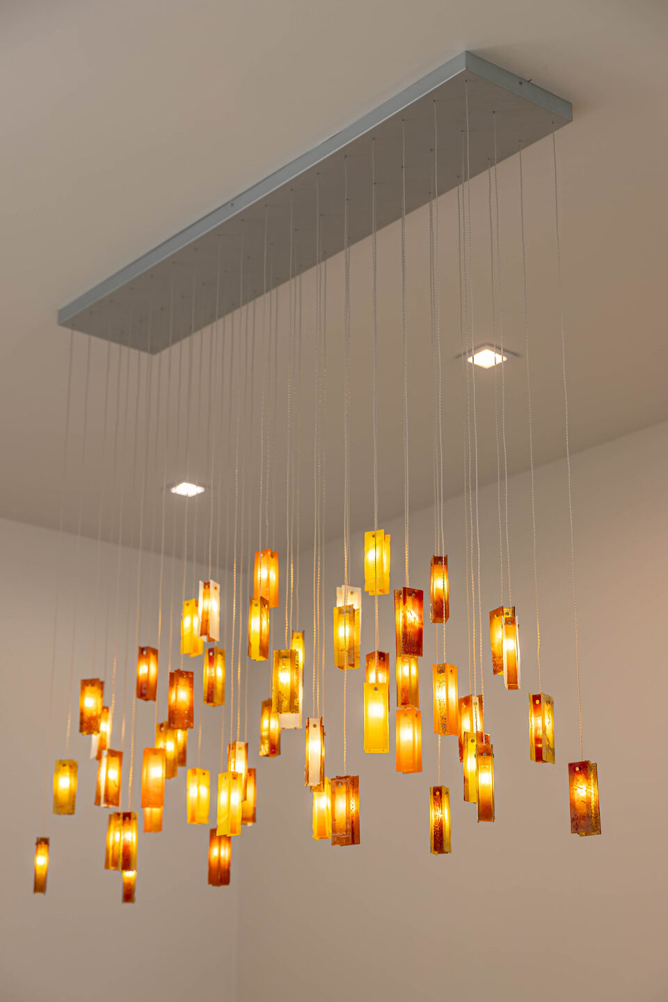 Close-up of the Sunbeam chandelier featuring handcrafted glass in layered amber and warm natural tones.