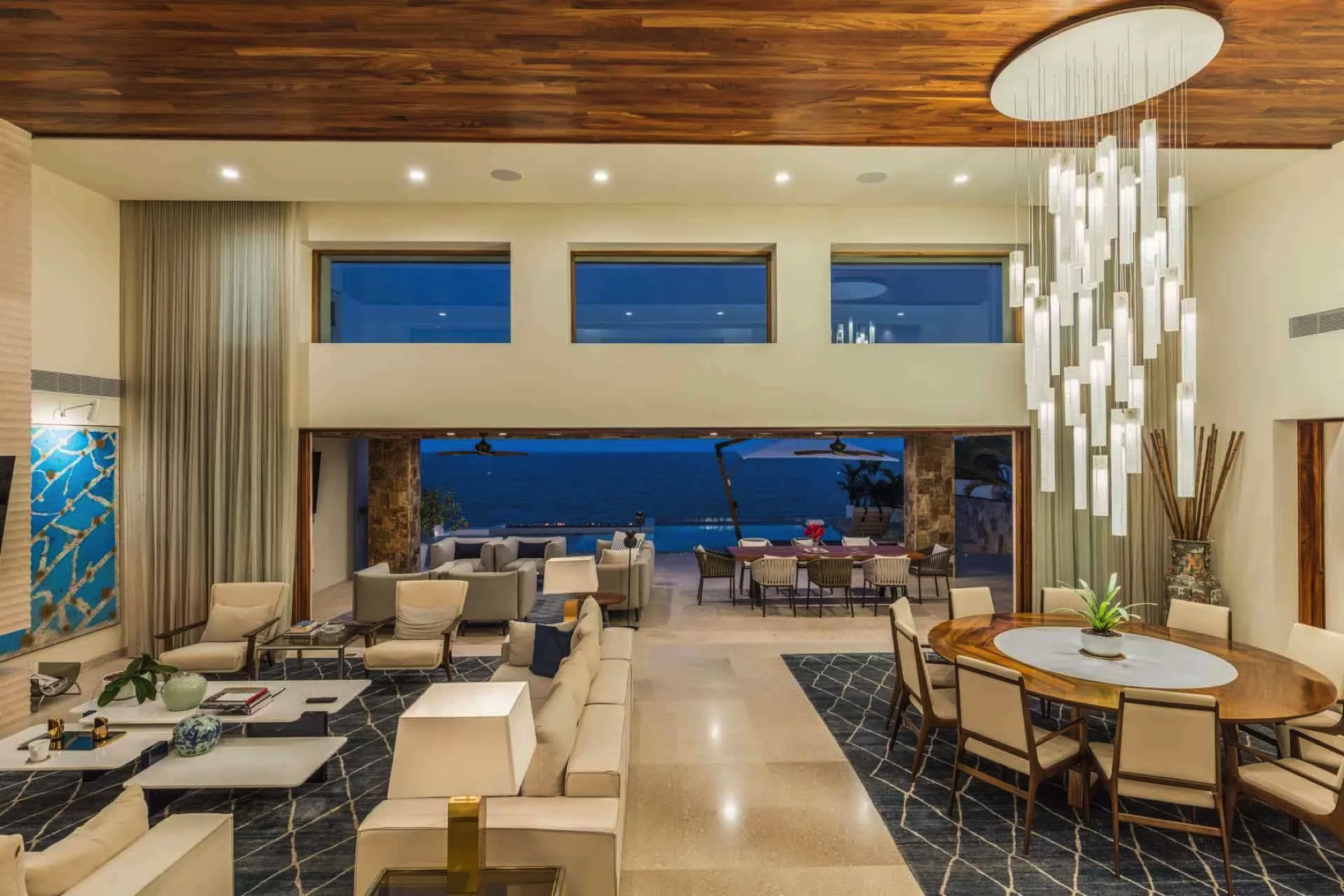 Custom glass lighting adds a vertical sculptural element to the double-height oceanfront living space.
