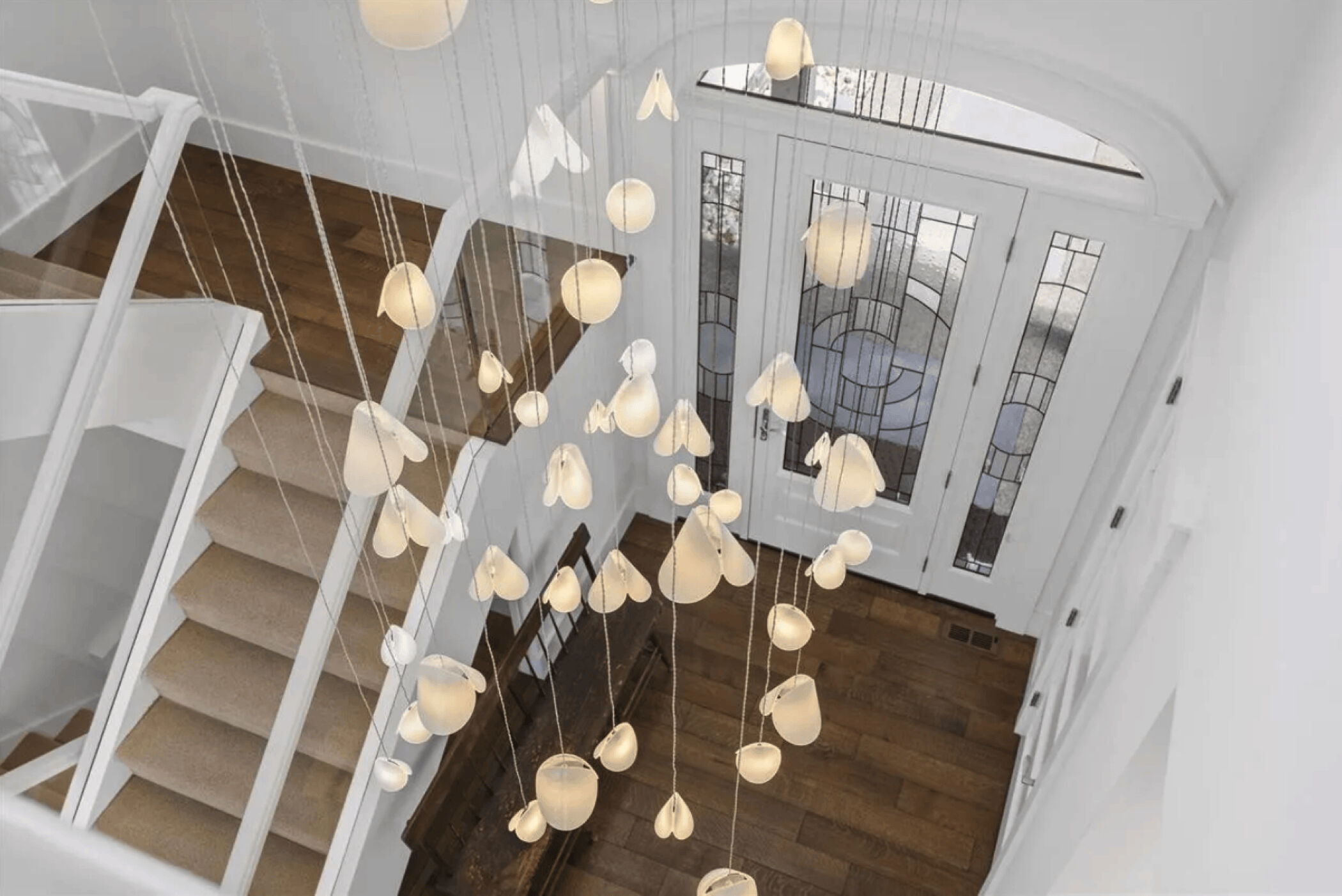 Overhead view of the cascading art glass chandelier in the double-height entrance and staircase.