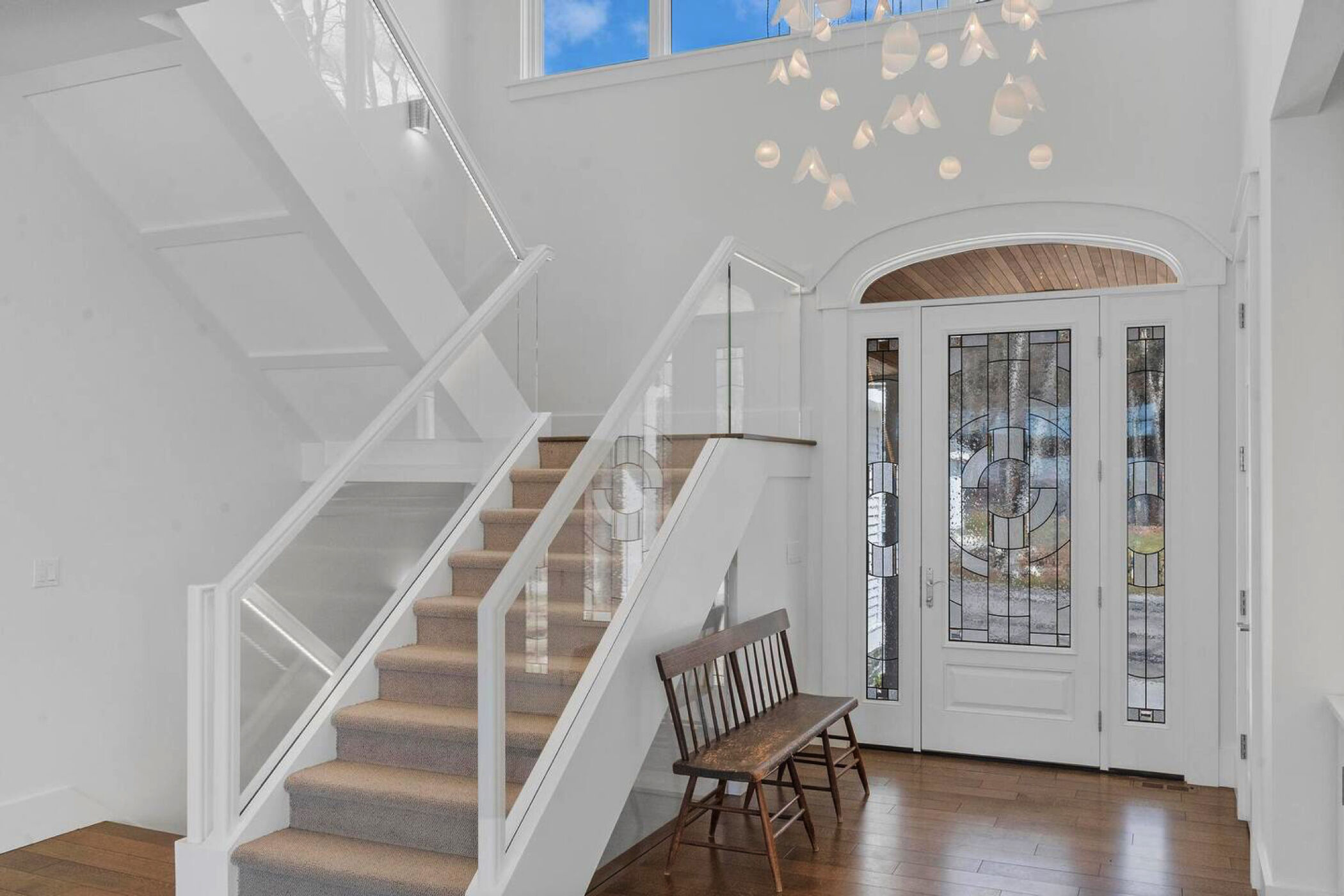 Handcrafted glass chandelier creating a soft sculptural focal point in the light-filled stairwell.