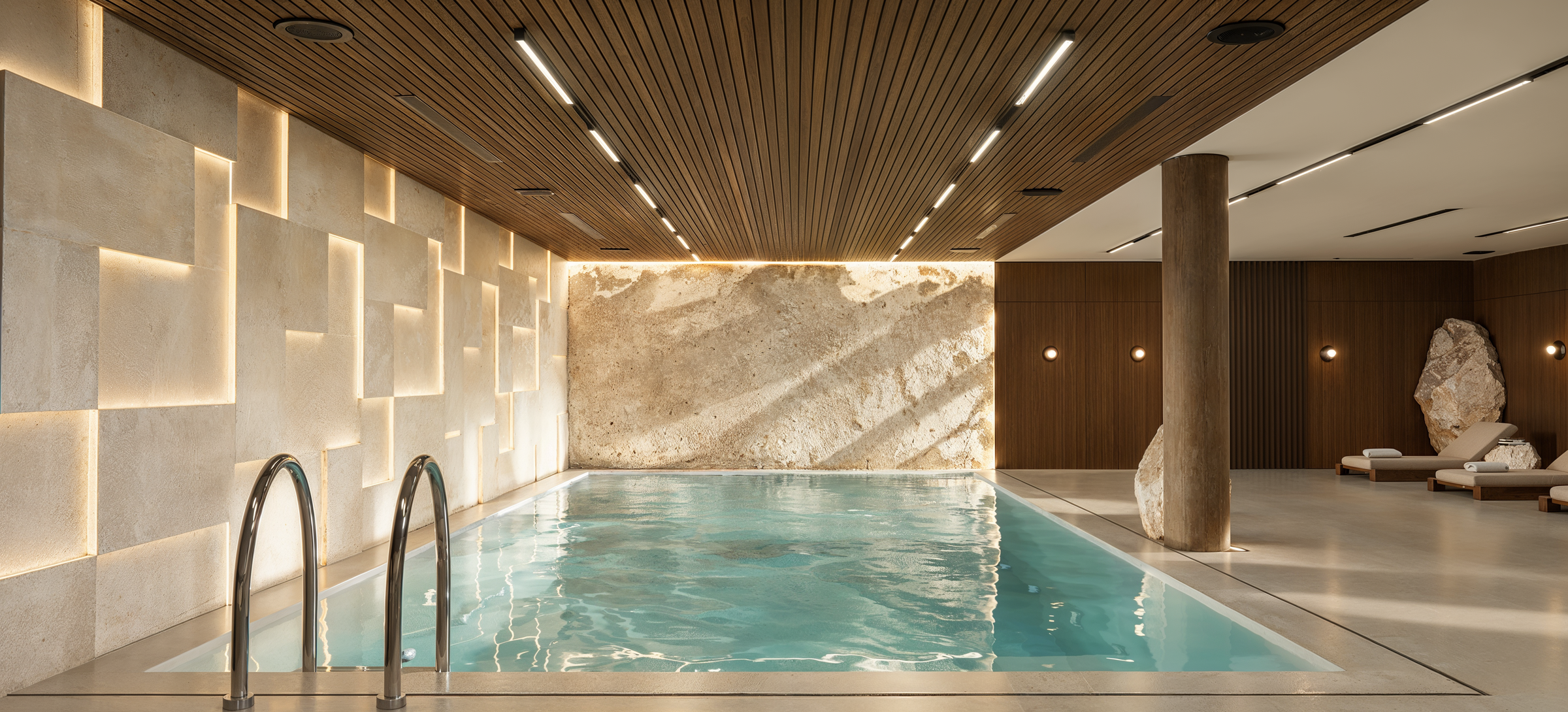 The indoor swimming pool combines natural stone, timber ceiling treatments, and integrated lighting to create a private wellness environment designed for year-round relaxation.
